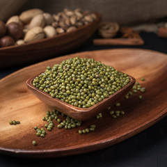 cereals and grains on a square wooden bowl and oval wooden tray on a dark background and burlap