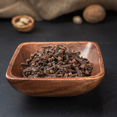 spices seasonings and grains on a square wooden bowl on a dark background and burlap