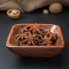 spices seasonings and grains on a square wooden bowl on a dark background and burlap