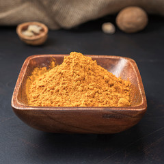 spices seasonings and grains on a square wooden bowl on a dark background and burlap