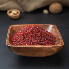 spices seasonings and grains on a square wooden bowl on a dark background and burlap