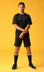Young African-American football player on color background