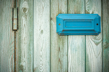 Blue rectangular address plate / mailbox on an old shabby turquoise fence
