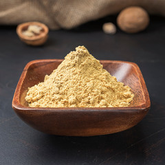 spices seasonings and grains on a square wooden bowl on a dark background and burlap