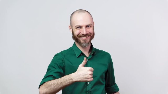 Happy bearded man wearing shirt showing thumbs up sign over white background. Good job, very well.