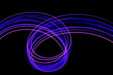 Long exposure photograph of neon purple streaks of light in an abstract swirl, parallel lines pattern against a black background. Light painting photography.