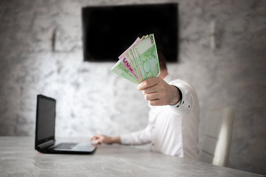 Biznesmen w biurze, banknoty euro w ręce