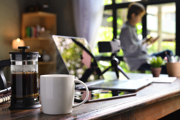 A coffee press and a cup on a work desk with a person working from home