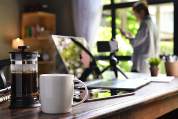 A coffee press and a cup on a work desk with a person working from home