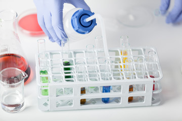 Lab. A technician in rubber gloves dilutes tested substance.