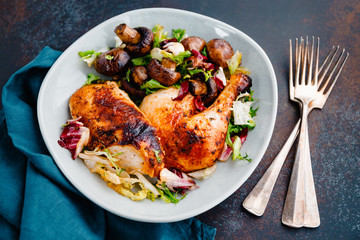 Roasted chicken leg and breast with fresh salad and champignons on a plate.