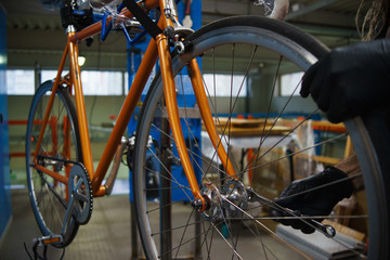 Obraz premium Workshop worker performs maintenance work and restores bicycle.