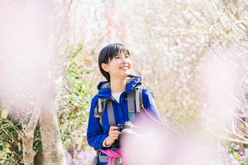 ハイキング中一眼レフで植物を撮る女性