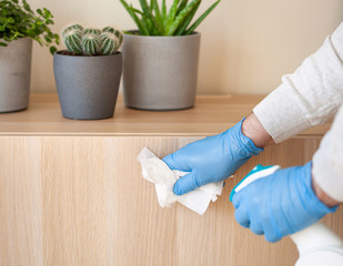 man hands in gloves disinfecting chest of drawers handle, killing virus on surface