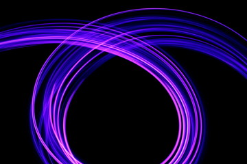 Long exposure photograph of neon purple streaks of light in an abstract swirl, parallel lines pattern against a black background. Light painting photography.