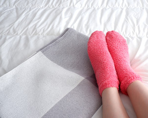 Beautiful smooth legs protrude from under the blanket, in soft pink socks.