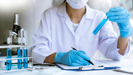 Fototapeta premium Scientist wear lab coat and protective wear are working with research or doing investigations with test tubes in experiment, Laboratory and development concept