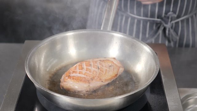 Cooking classic Confit Duck in French restaurant, close-up. Duck meat being fried in hot pan with olive oil. Slow motion footage. Shot in hd.