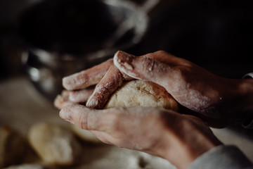 cook with bare hands in flour sculpts dough pies on the kitchen table © Ilya.K