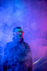 Fototapeta na wymiar Studio shot of bearded young man in red spiral eyeglasses standing in the smoke
