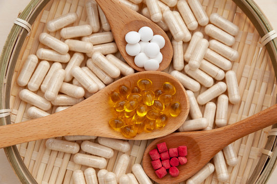 Nutritional supplements in wooden spoons inside a braided bamboo plate. Close-up. Concept: Healthy lifestyle.