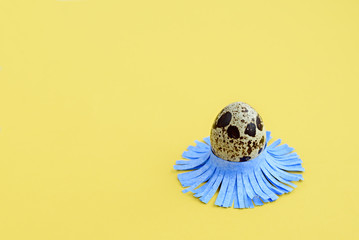 Decorated quail egg on a yellow background. Children's creativity, crafts