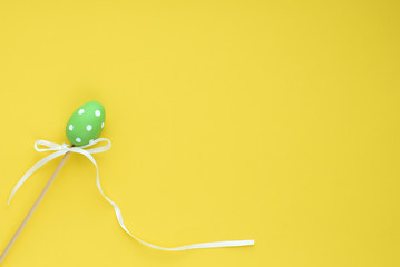 Decorative green easter egg on a yellow background