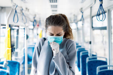 Woman wearing surgical protective mask coughing in a public transportation
