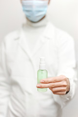 Close up view of female physician hands showing a personal antiseptic or sanitizer. Covid-19 protection measures. Doctor in white medical gown at clean white background.