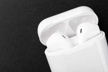 Modern wireless bluetooth headphones with charging case on a dark black background.