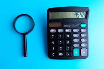 Concept of medical expenses or medical insurance for blog title and header. Stethoscope,white calculator and magnifying glass on wooden background.