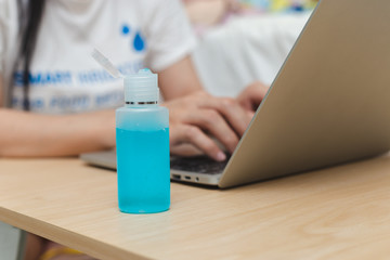close up sanitizer gel for hand hygiene coronavirus prevention with background woman work at home and laptop.