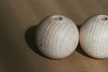 Two wooden beads lie on a cardboard in the rays of sunlight and cast a shadow. The theme of ecology and recycling of materials.