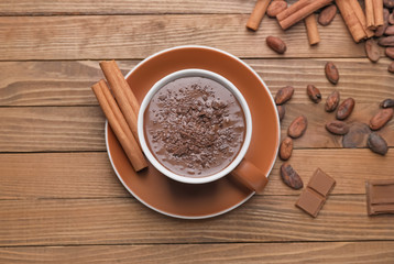 Cup of hot chocolate and cinnamon on wooden background