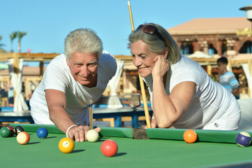Portrait of smiling senior couple playing billiard together