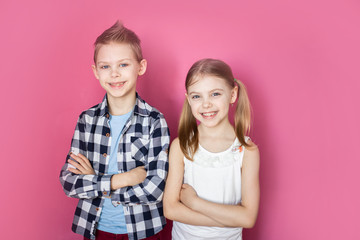 cute children, brother and sister 7-9 years old on a pink background smiling