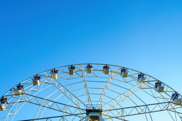 Bottom view of part white ferris wheel on background of blue sky in sunny day, copy space