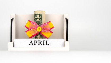 perpetual calendar with wooden cubes. celebrating the birthday of the dollar on April 01. dollar tied with a festive bow. American currency, paper currency notes. money as gift, win or bonus.