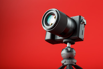 Professional camera on a tripod, on a red background. Record videos and photos for your blog, reportage