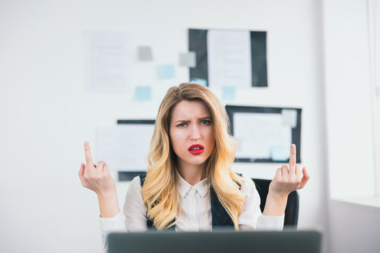 young beautiful businesswoman manager with red lipstick works in her modern office, looks angry showing fuck off sign with bith hands, body language concept