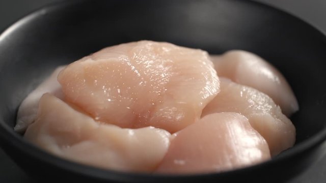 Salt falls down in slow motion to the spinning bowl with raw chicken brests, cooking the chicken nuggets, diet meal, salting the dish, tabletop slowmotion video, Full HD 240fps 10 bit Prores HQ
