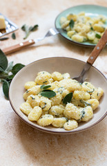 Italian homemade gnocchi with butter, cheese and sage served in two plates on a light marble table. Italian food. Close-up