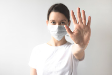 Coronavirus concept. Girl wearing a protective medical mask shows a gesture stop. Protect your health. Stop the virus and pandemic covid-19