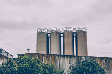 Four industrial metal storage tanks above a wall © funkenzauber