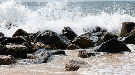 Ocean waves crashing on a jetty of rocks on the beach
