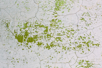 Cracked wall with old layers of green paint in abandoned house. Old cracked background. Abstract.