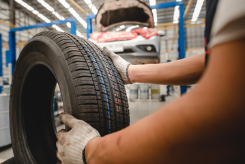 Auto mechanic is changing new tires at the tire changing service shop. Changing tires in winter and...