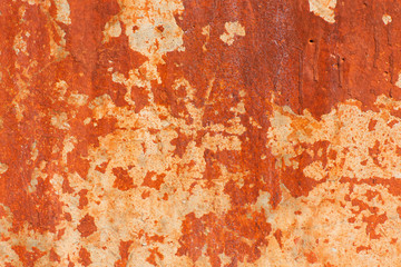 Structure of a strongly exfoliating old paint of orange color. Abstract background. Texture, pattern, background. Old wall with remains of cracked paint orange, closeup. 