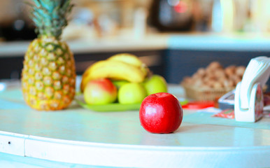  Red apple and diverse fruits on a table in a modern kitchen. Useful Conception of proper nutrition