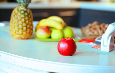  Red apple and diverse fruits on a table in a modern kitchen. Useful Conception of proper nutrition
